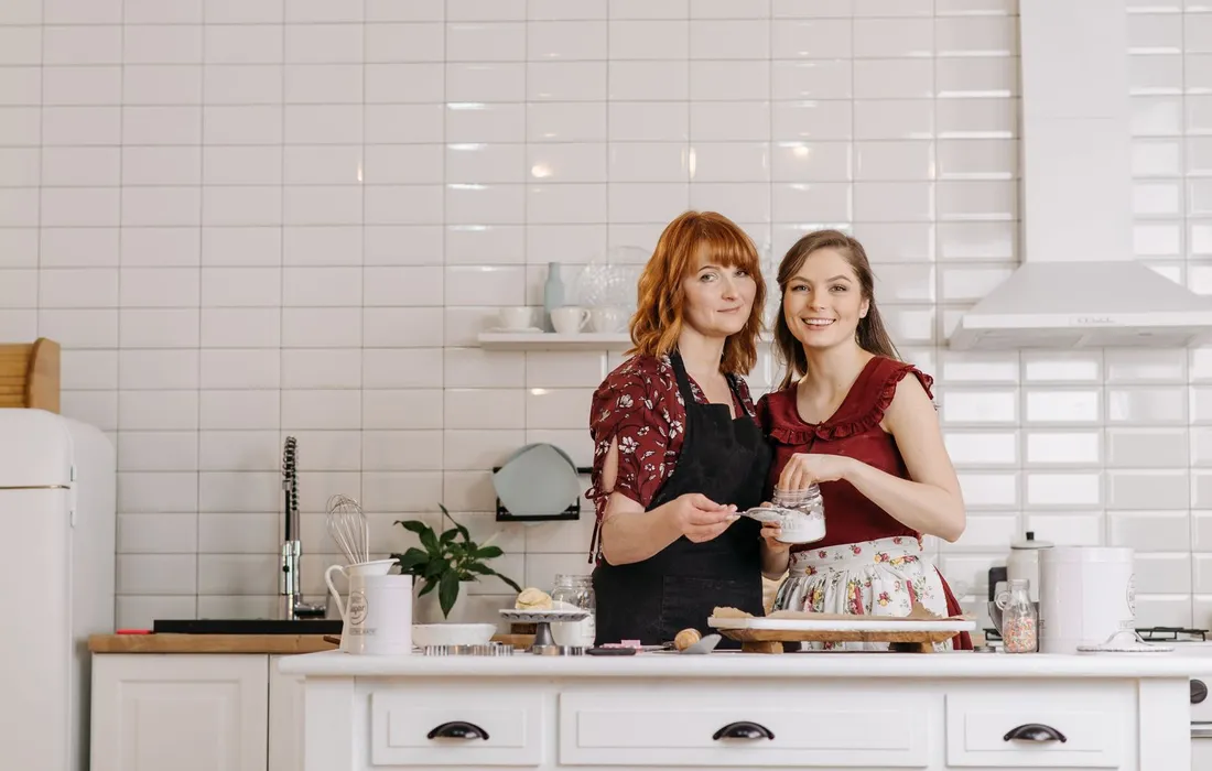 Mujer junto a una niña en la cocina de su vivienda